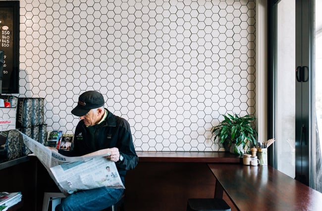 A man reading a newspaper by the counter at Big Fig in Wānaka.