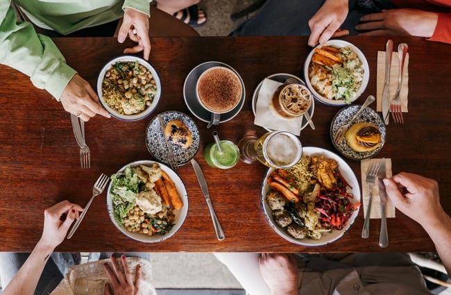 A flatlay of plates on a table with four people gathered around at Big Fig in Wānaka.