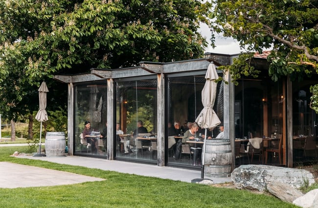 Looking across the grass to the enclosed dining area at Bistro Gentil underneath established trees.