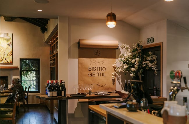 The interior of Bistro Gentil where a big roll of brown paper with handwritten lettering is mounted on the wall beneath a lantern.