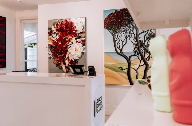 Counter area at Black Door Gallery with paintings hanging on the wall behind.