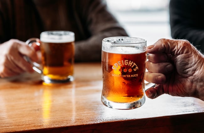 Hands holding a glass of beer.