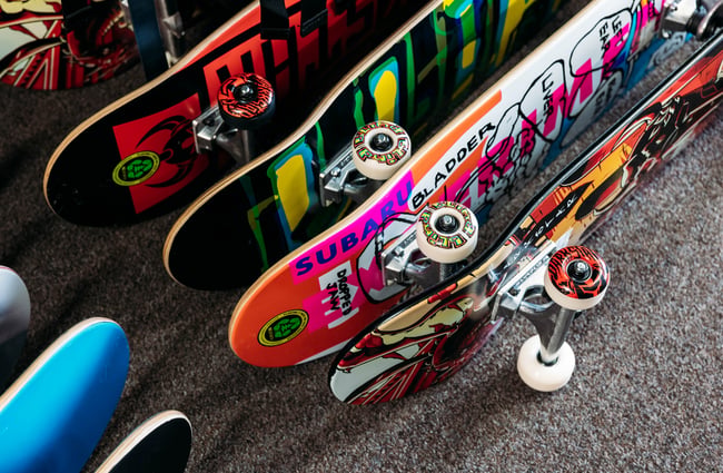 A close up of colourful skateboards lined up on a floor.