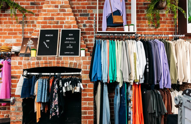 Colourful clothes up against a brick wall inside a retail store.