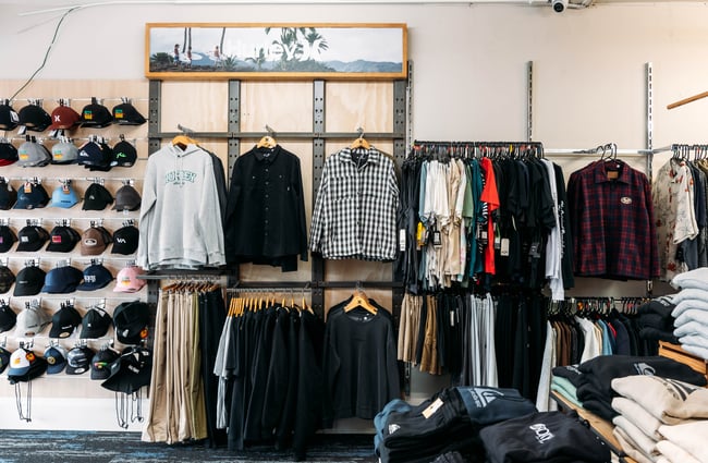 Dark clothes on racks inside a retail store.