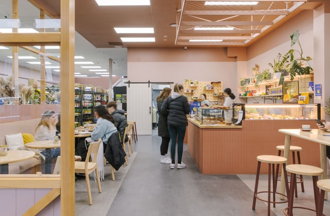 Customers sitting at tables, customers lining up to order at the counter at Blue Moon Bakehouse.