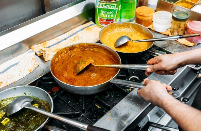 A close up of curries being cooked on a stove.