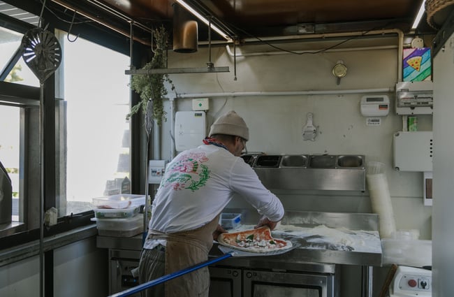 A man making a pizza in a kitchen.