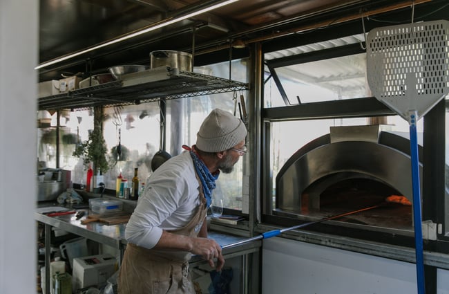 A man placing a pizza in an oven.