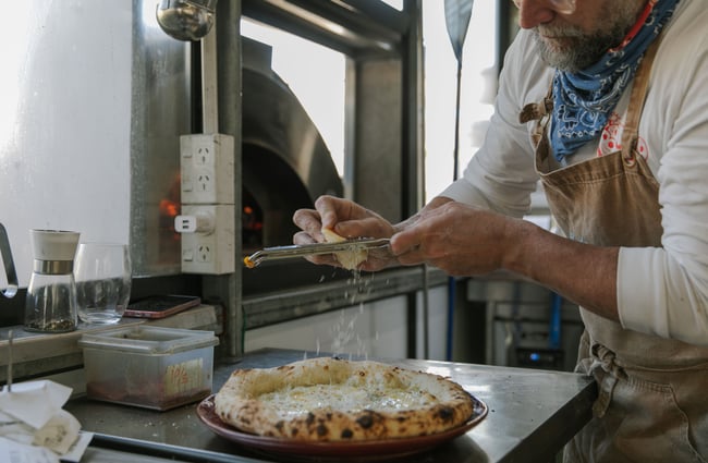 Parmesan being grated on to a pizza.