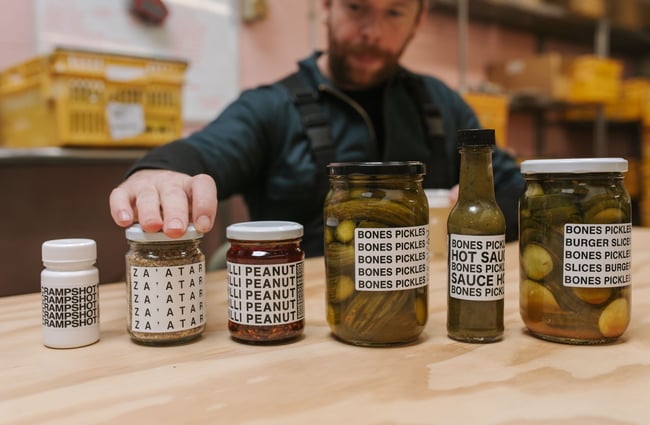 Chef screwing a lid on a lineup of products at Bones Pickles.
