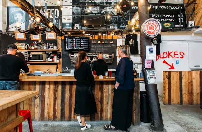 Two ladies ordering at the wood panelled counter with big festoon lights hanging above them.