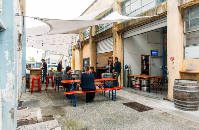 The exterior of the Bootleg Brewery with big orange tables and benches outside.