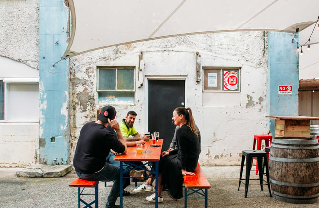 People seating around a bright orange table in the outdoor courtyard.