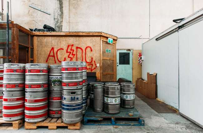 Big silver kegs of beer stacked up on wooden pallets.