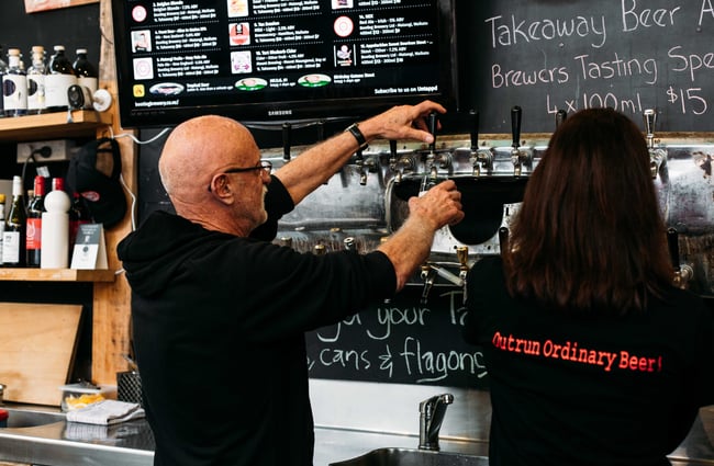 A man behind the counter pouring beer from the tap.
