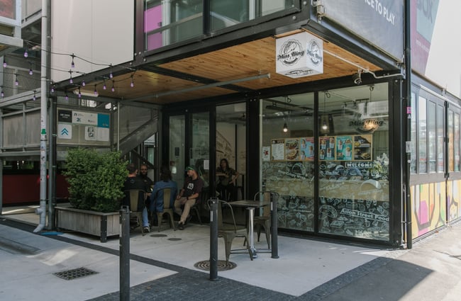 People dining in the shade outside and inside Miss Bing in BOXed Quarter in Christchurch.