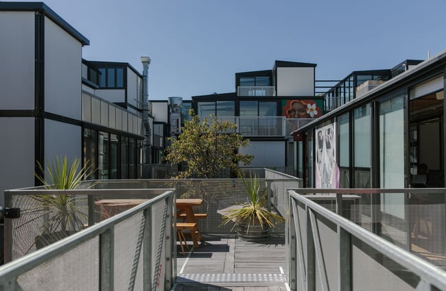 The view from an upper level exterior walkway of BOXed Quarter; metal mesh panels line the balustrade and large format artworks are visible on walls that are not glazed.