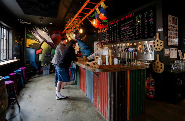 Two patrons chat with the bartender up at the bar at Brew Moon.