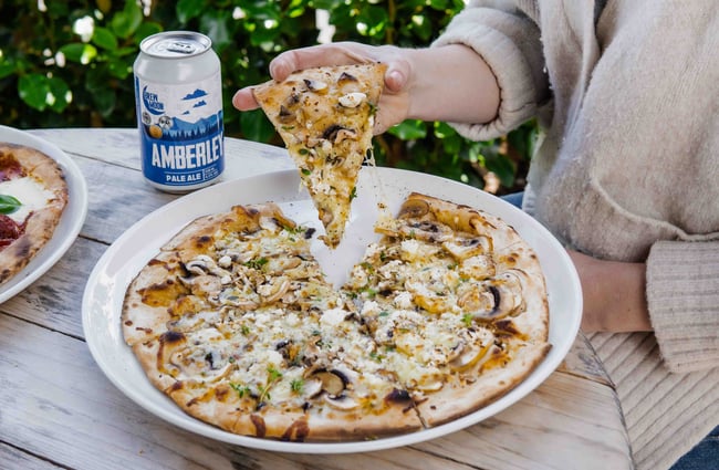 Close up of a person picking up a slice of pizza.