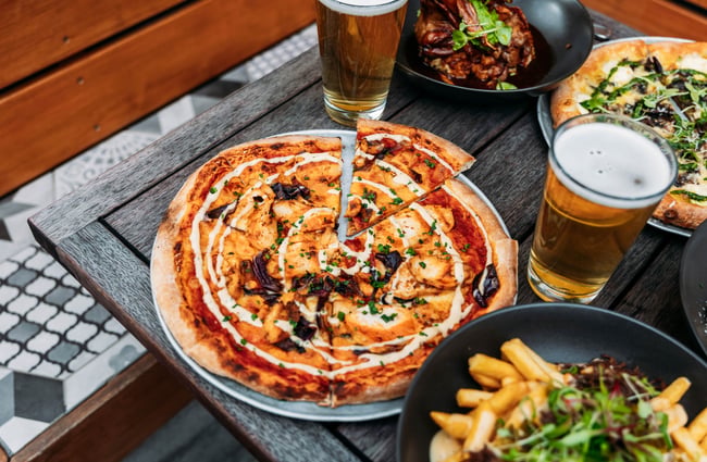 Pizza and pints of beer flatlay on a table.