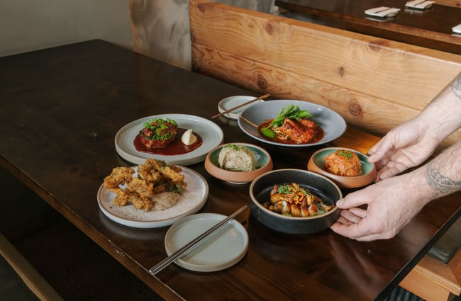 Hands holding plates of food.
