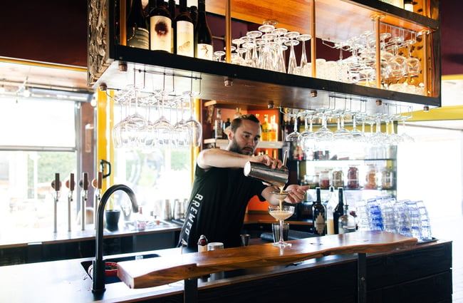 Bartender pouring a cocktail at Brewed As.