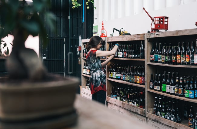 Looking at labels of the bottles on a shelf.