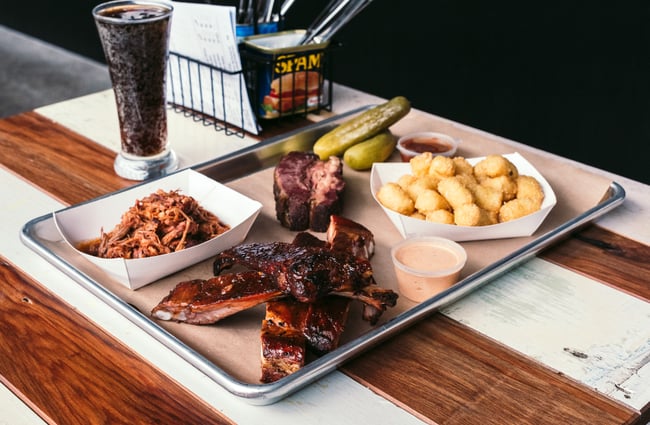Food on a tray on a white and wooden table.