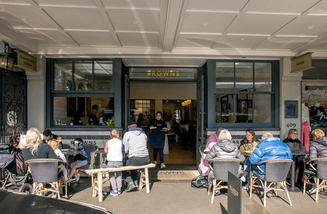 Customers sitting outside a cafe around tables and chairs.