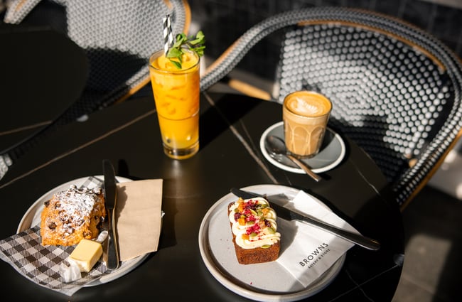 Sweet treats and glasses of juice on a table in the sunshine.