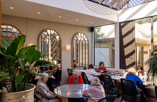 Customers dining outside in a covered part of a cafe.