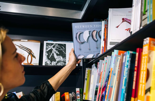 Close up of a women grabbing down a book. from the shelf.