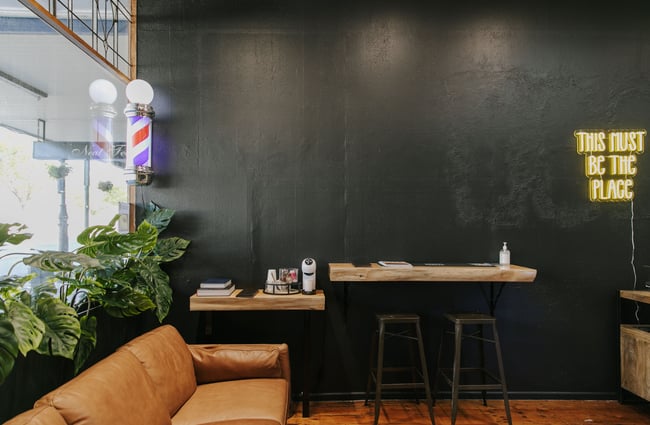 A black wall and a brown leather couch in Bruce's Barber.
