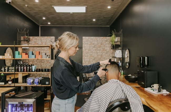 A female staff member cutting the hair of a male client.