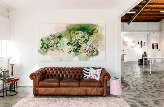 A brown leather couch in a gallery.