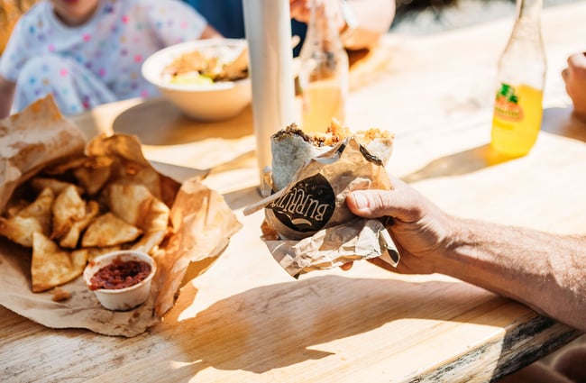 A hand holding a half-eaten burrito.