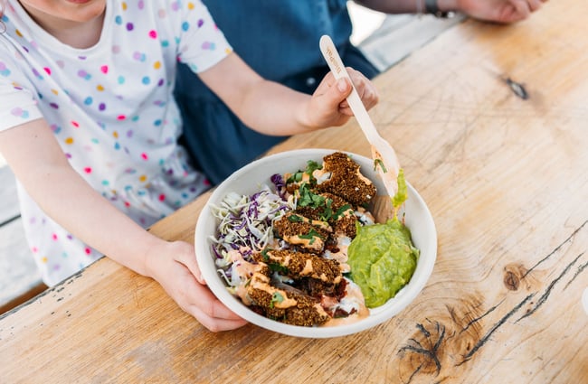 A kid eating a burrito bowl.
