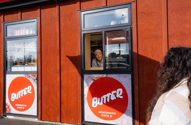A man chatting to a woman from a cafe window on a sunny day.