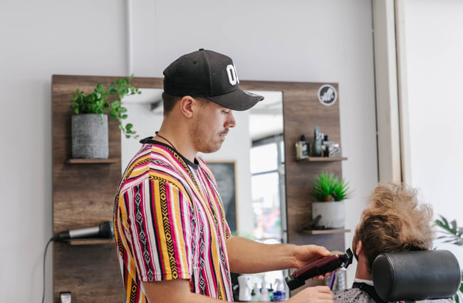 Barber giving customer beard trim.