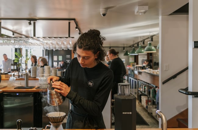 A staff member making a V60 pour-over coffee.
