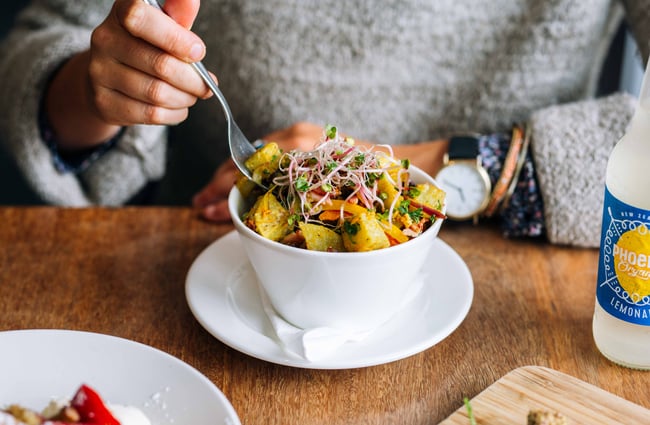 Woman eating bowl of salad.