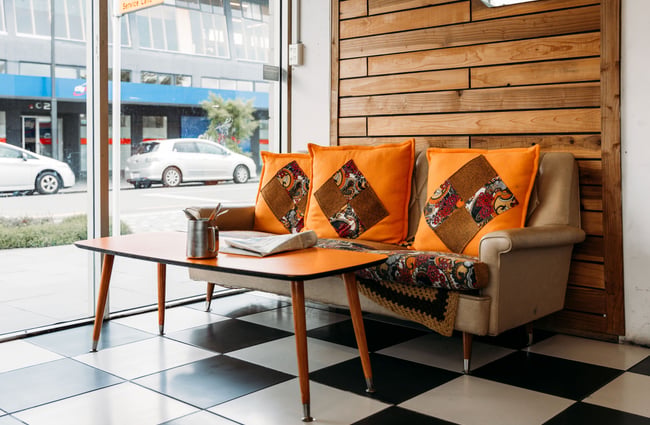 A vintage couch and coffee table at the front of a cafe.