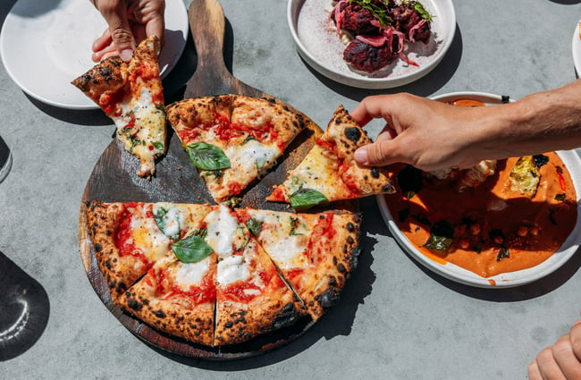 Hands grabbing at slices of pizza.