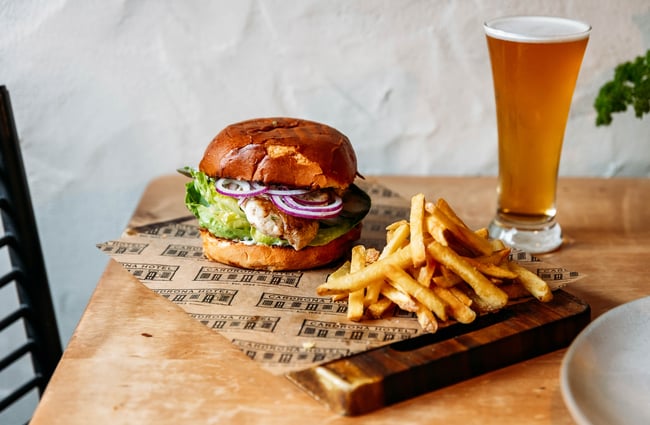 Close up of a burger on a board with fries and a pint of beer at Cardrona Hotel.