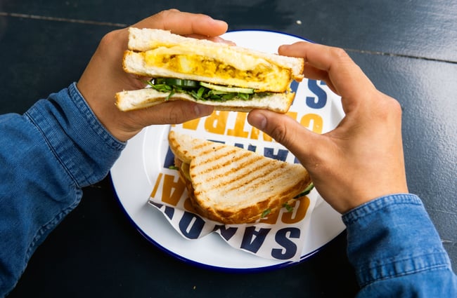 A close up of two hands holding a sandwich.