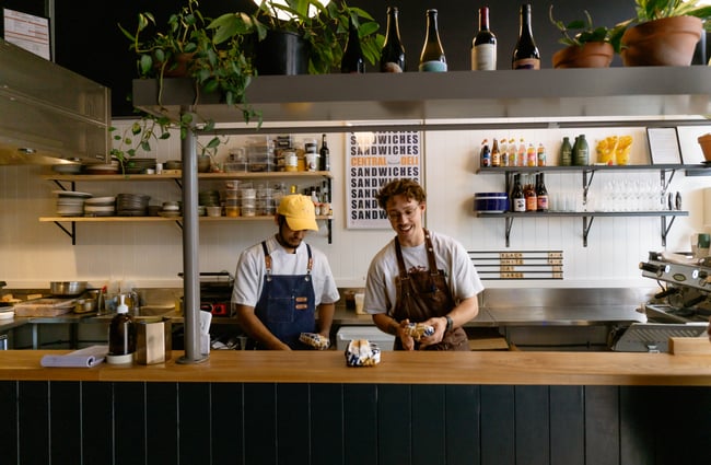 Two staff members working behind the counter at Central Deli Sandwiches.