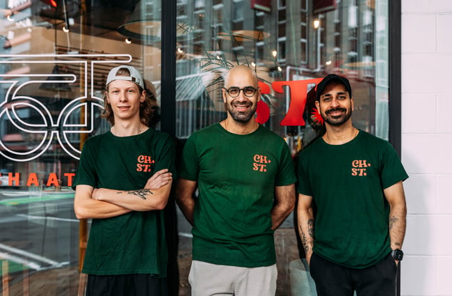 Three men outside a restaurant wearing matching t-shirts.