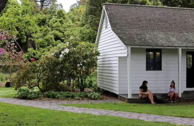 People sitting outside historic house at Christchurch Farmers Market.