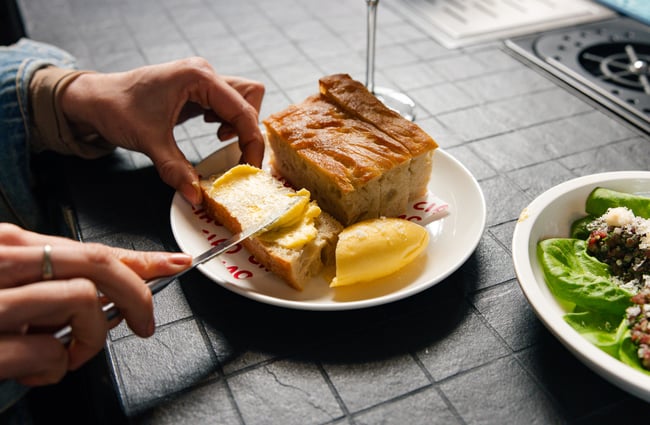Customer spreading butter on focaccia at Ciao within The Welder.